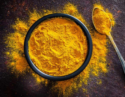 Vivid yellow turmeric powder in a small bowl, finely ground, displaying its bright, rich color and used for flavoring, coloring, and medicinal purposes in cooking.